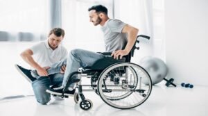 Physiotherapist massaging leg of handicapped man in wheelchair